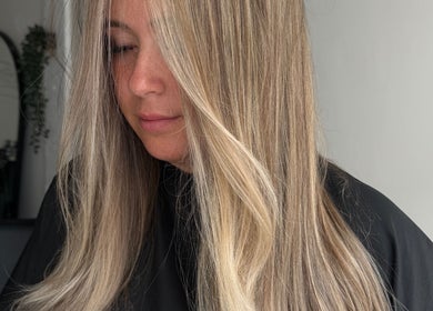 Blonde hair styling at Coloured by Madison, Plymouth, England, GB. Smooth, highlighted strands framing a woman's face.