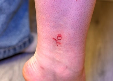 Delicate red rose tattoo on ankle at G’lamore Ink & Beauty in Birmingham, England, GB.
