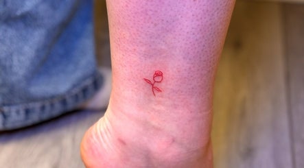 Delicate red rose tattoo on ankle at G’lamore Ink & Beauty in Birmingham, England, GB.
