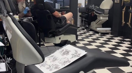 Tattoo artist working at G’lamore Ink & Beauty, Birmingham, England, GB, with designs on display.