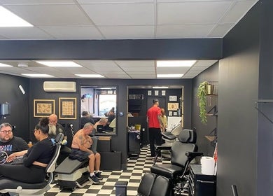Interior view of G’lamore Ink & Beauty, Birmingham, England, GB showcasing tattoo services with clients and artists.