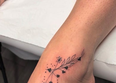 Delicate floral tattoo on ankle at G’lamore Ink & Beauty, Birmingham, England, GB.