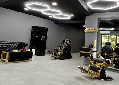 Interior modern la The Godfather Barbershop, București, București, RO, cu scaune de aur și mobilier elegant.