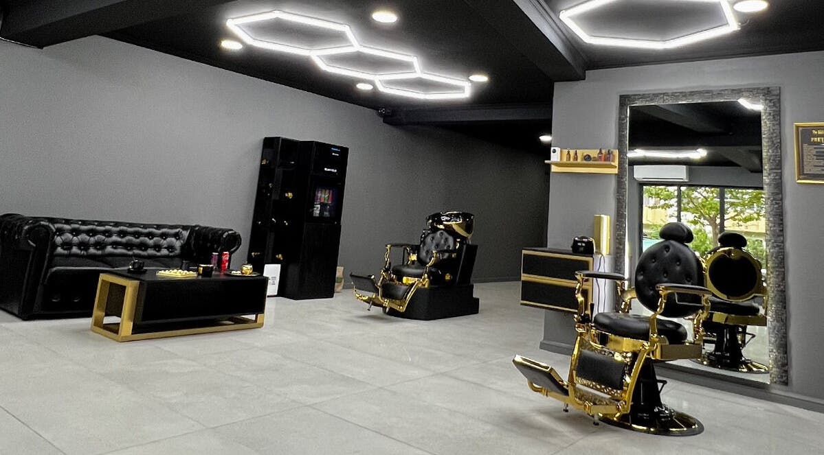 Interior modern la The Godfather Barbershop, București, București, RO, cu scaune de aur și mobilier elegant.