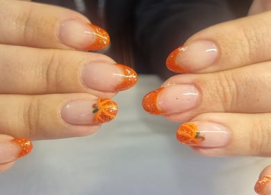 Stylish pumpkin-themed manicure at Krisu, Wolverhampton, England, GB. Features orange and glitter accents.