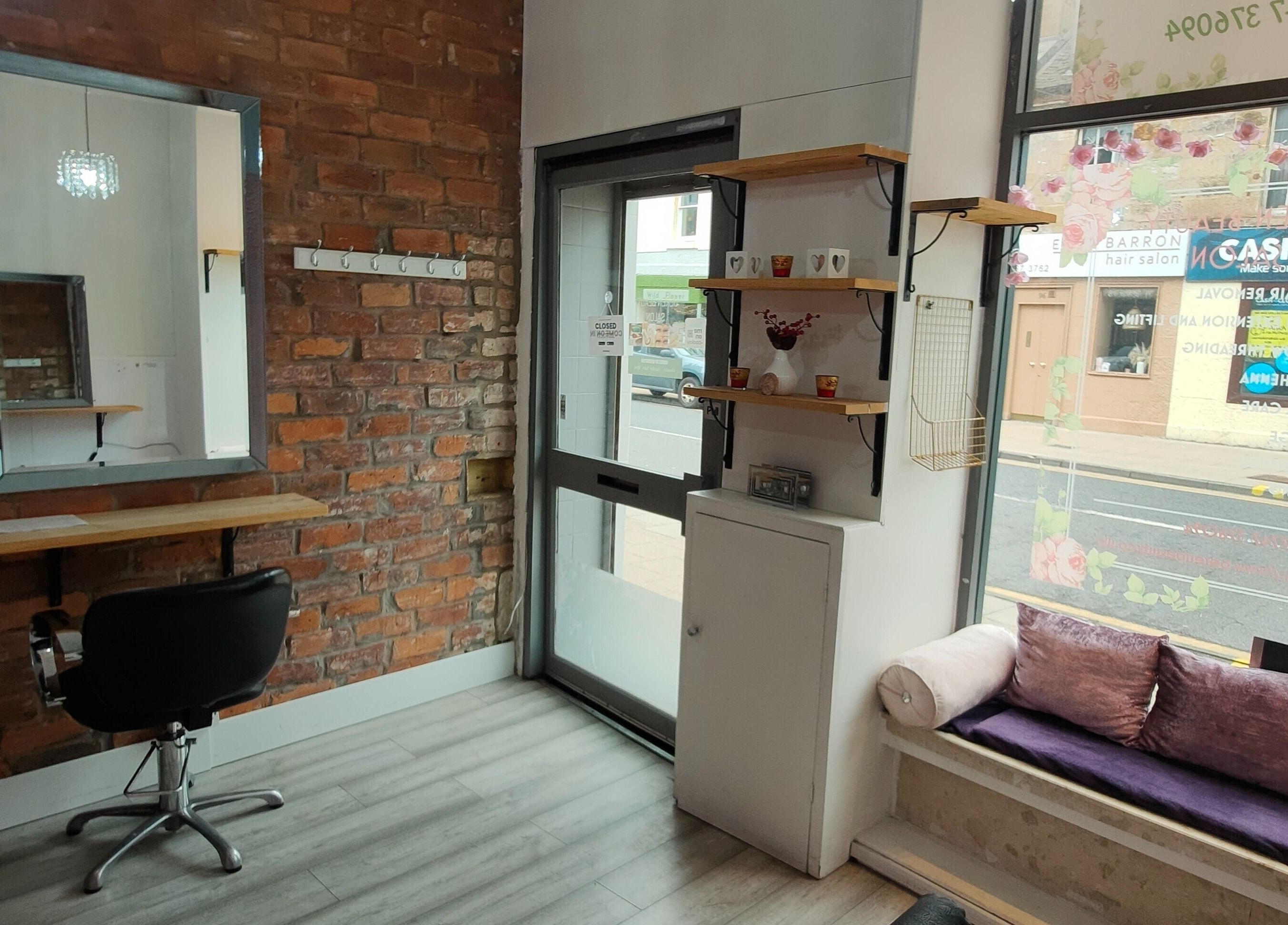 Cozy seating area and styling station at Beren Beauty Salon, Edinburgh, Scotland, GB featuring a mirror and brick wall.