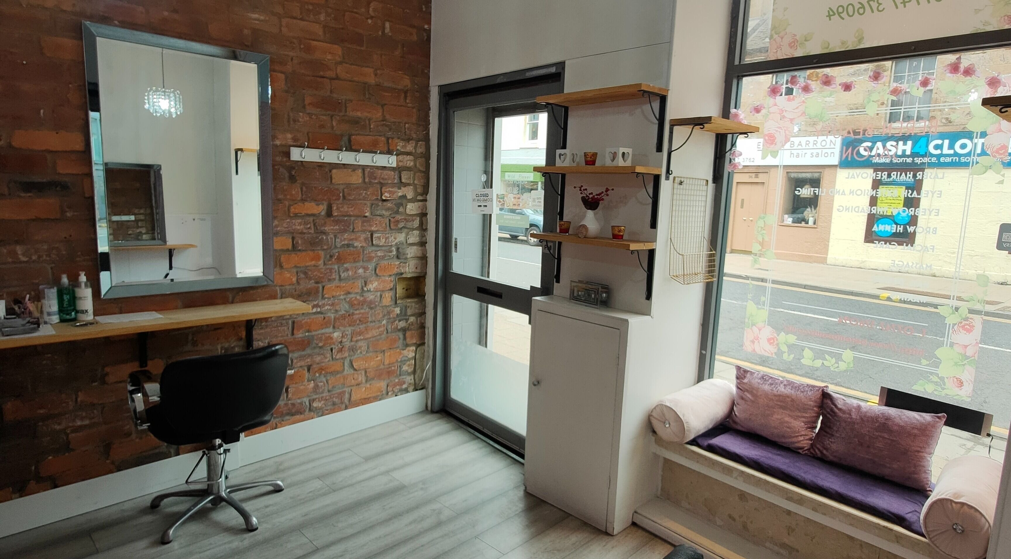 Cozy seating area and styling station at Beren Beauty Salon, Edinburgh, Scotland, GB featuring a mirror and brick wall.