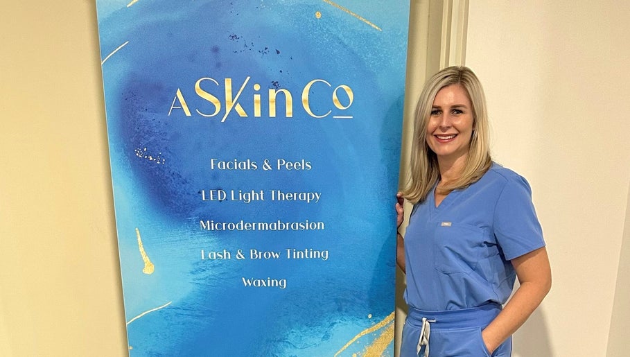 Professional at AskinCo in Mooloolaba, Queensland, AU, beside beauty services board.