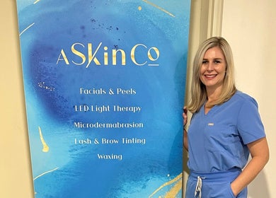 Professional at AskinCo in Mooloolaba, Queensland, AU, beside beauty services board.