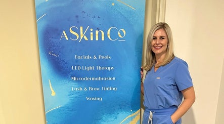 Professional at AskinCo in Mooloolaba, Queensland, AU, beside beauty services board.