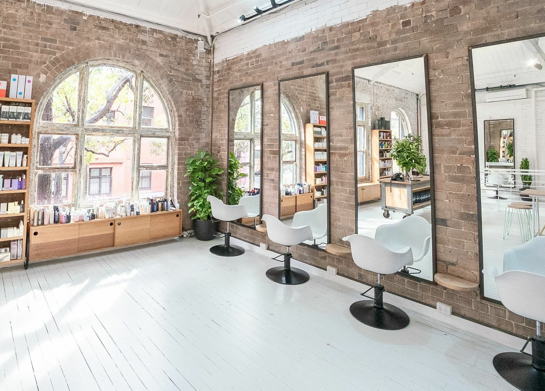 Bright, stylish salon interior at E+Co - Kippax Street, Surry Hills, New South Wales, AU with mirrors and chairs.