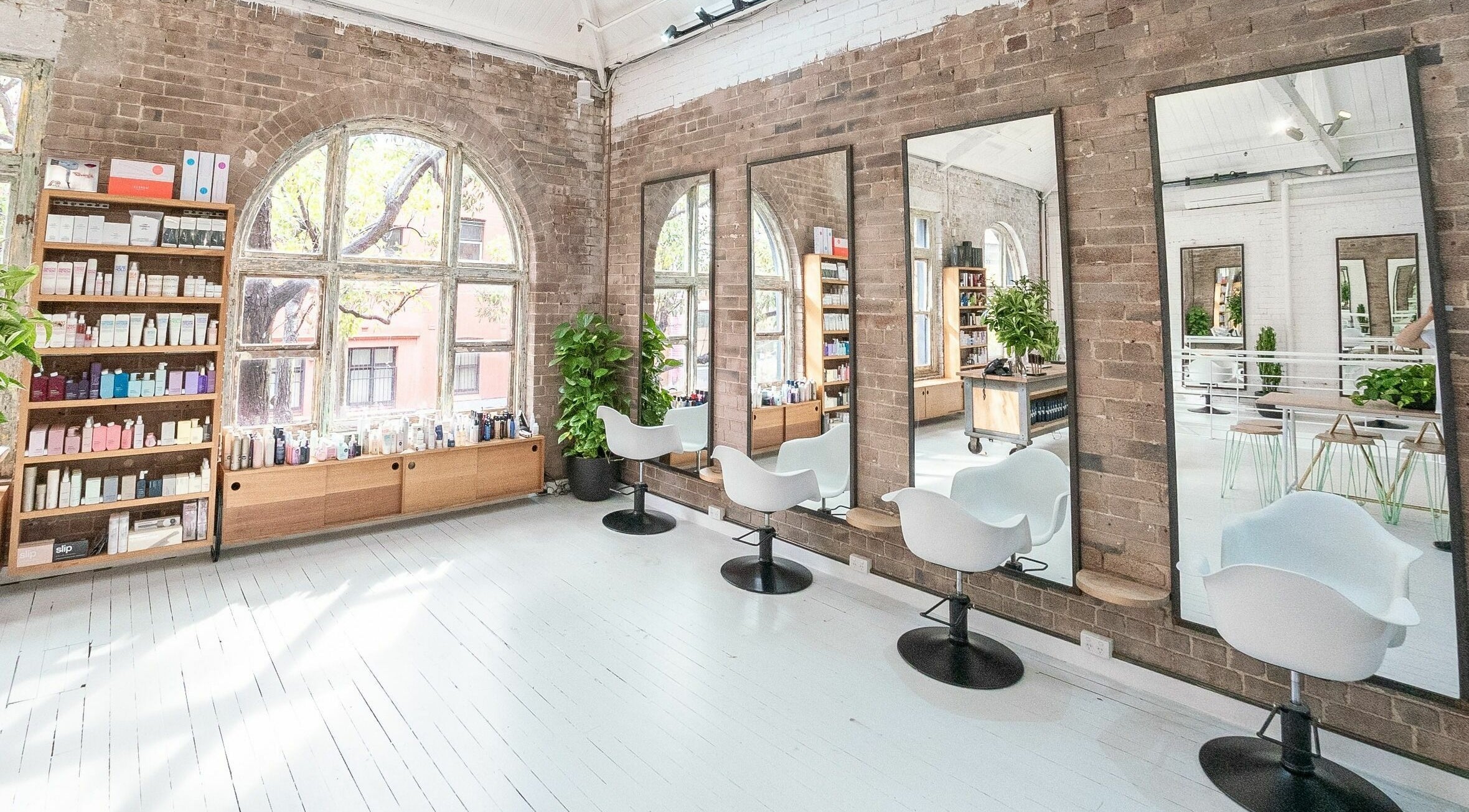 Bright, stylish salon interior at E+Co - Kippax Street, Surry Hills, New South Wales, AU with mirrors and chairs.
