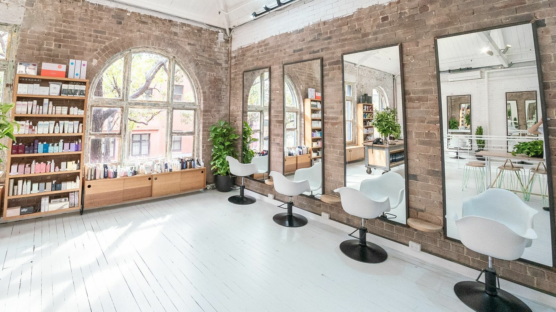 Bright, stylish salon interior at E+Co - Kippax Street, Surry Hills, New South Wales, AU with mirrors and chairs.