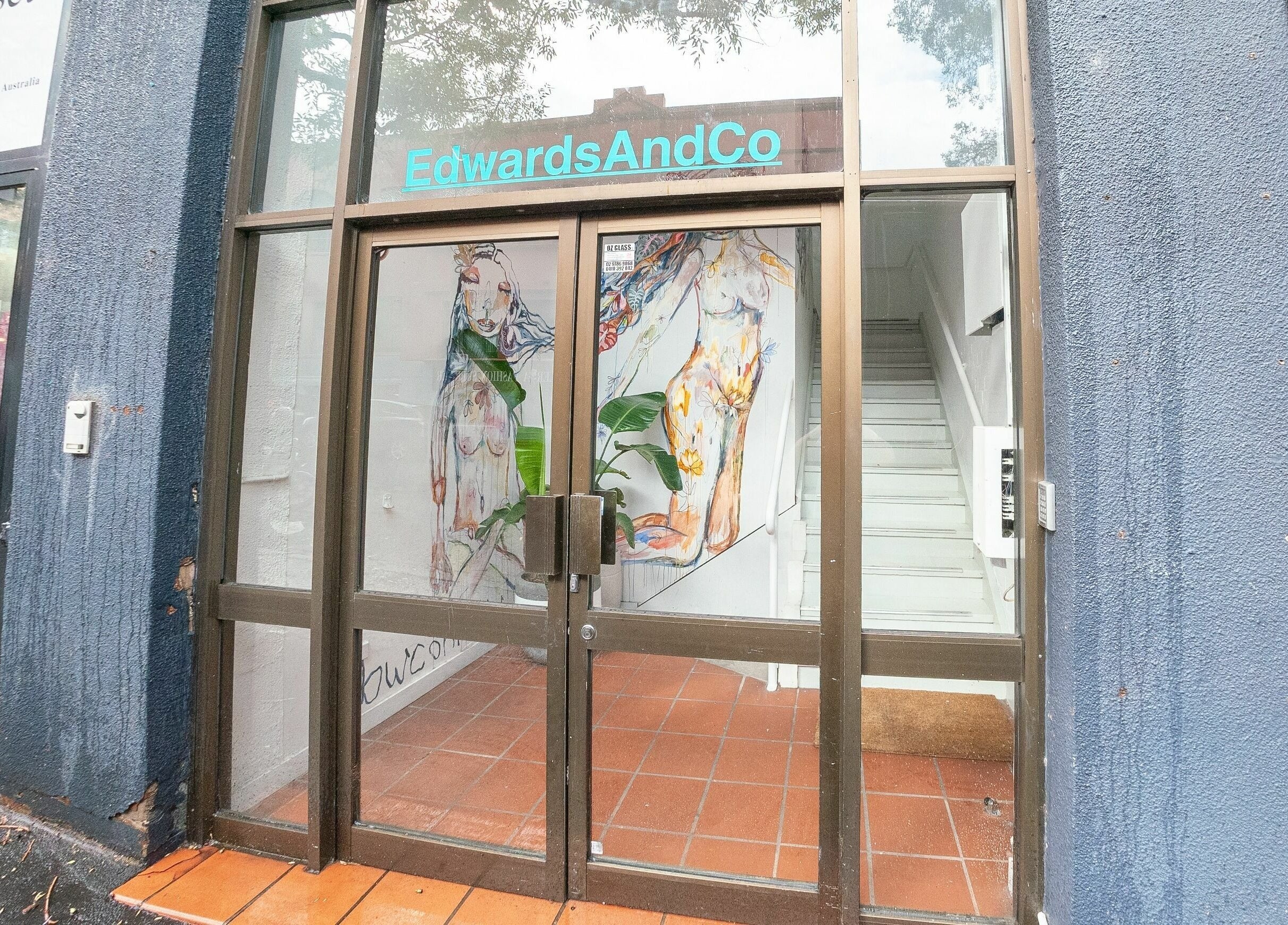 Entrance of E+Co - Kippax Street in Surry Hills, New South Wales, AU, featuring artistic murals on glass doors.