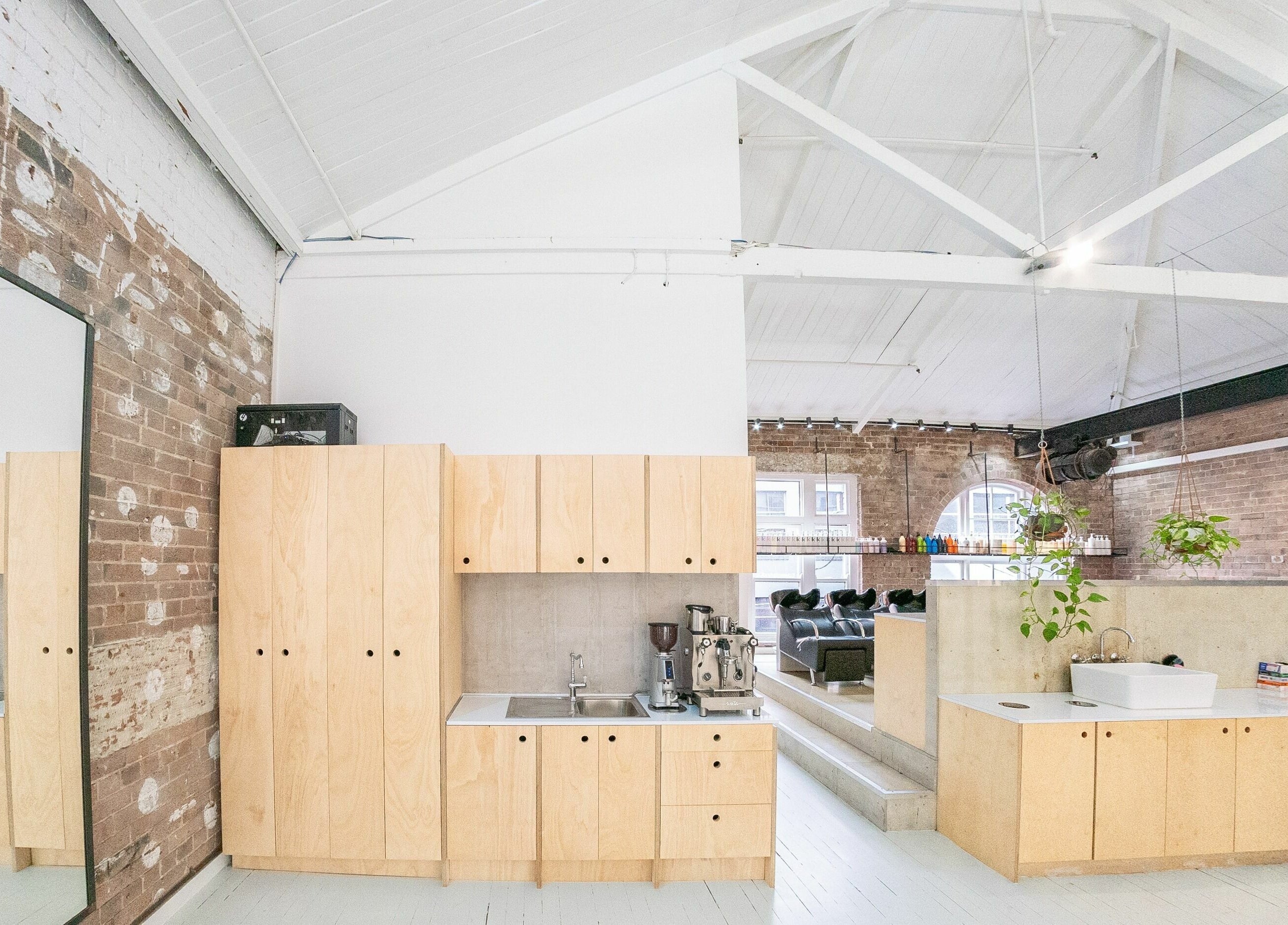 Chic salon interior at E+Co - Kippax Street, Surry Hills, New South Wales, AU with exposed brick and wooden cabinets.