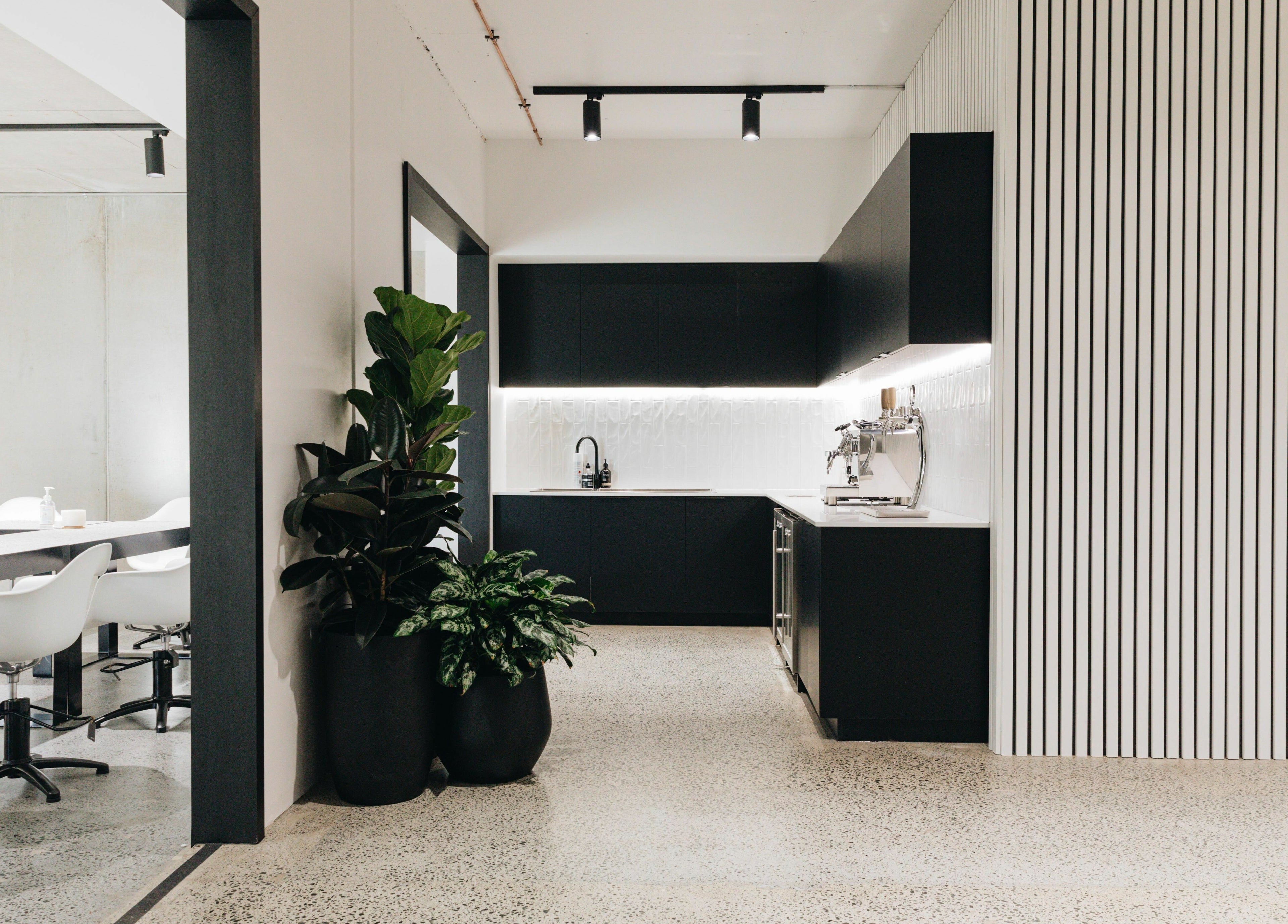 Stylish kitchen area in E+Co - Fortitude Valley, featuring modern seating and plants. Fortitude Valley, Queensland, AU.