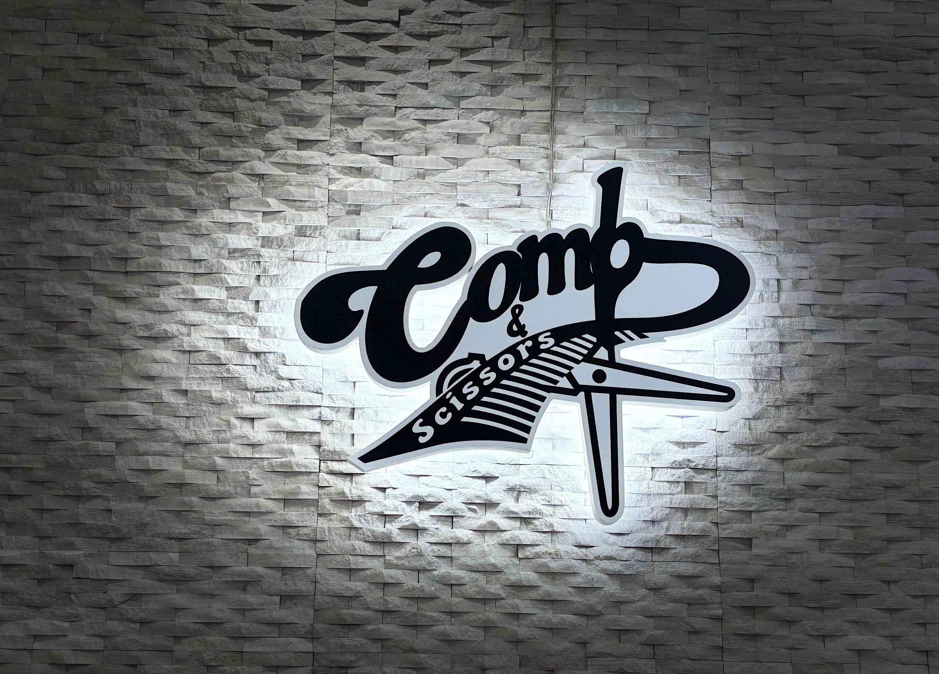 Comb and Scissors Gents Salon logo on textured wall in Dubai, AE.