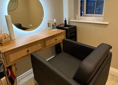 Cozy salon station at Extensions by Beth, Harrogate, England, GB with elegant black chair and wooden vanity.