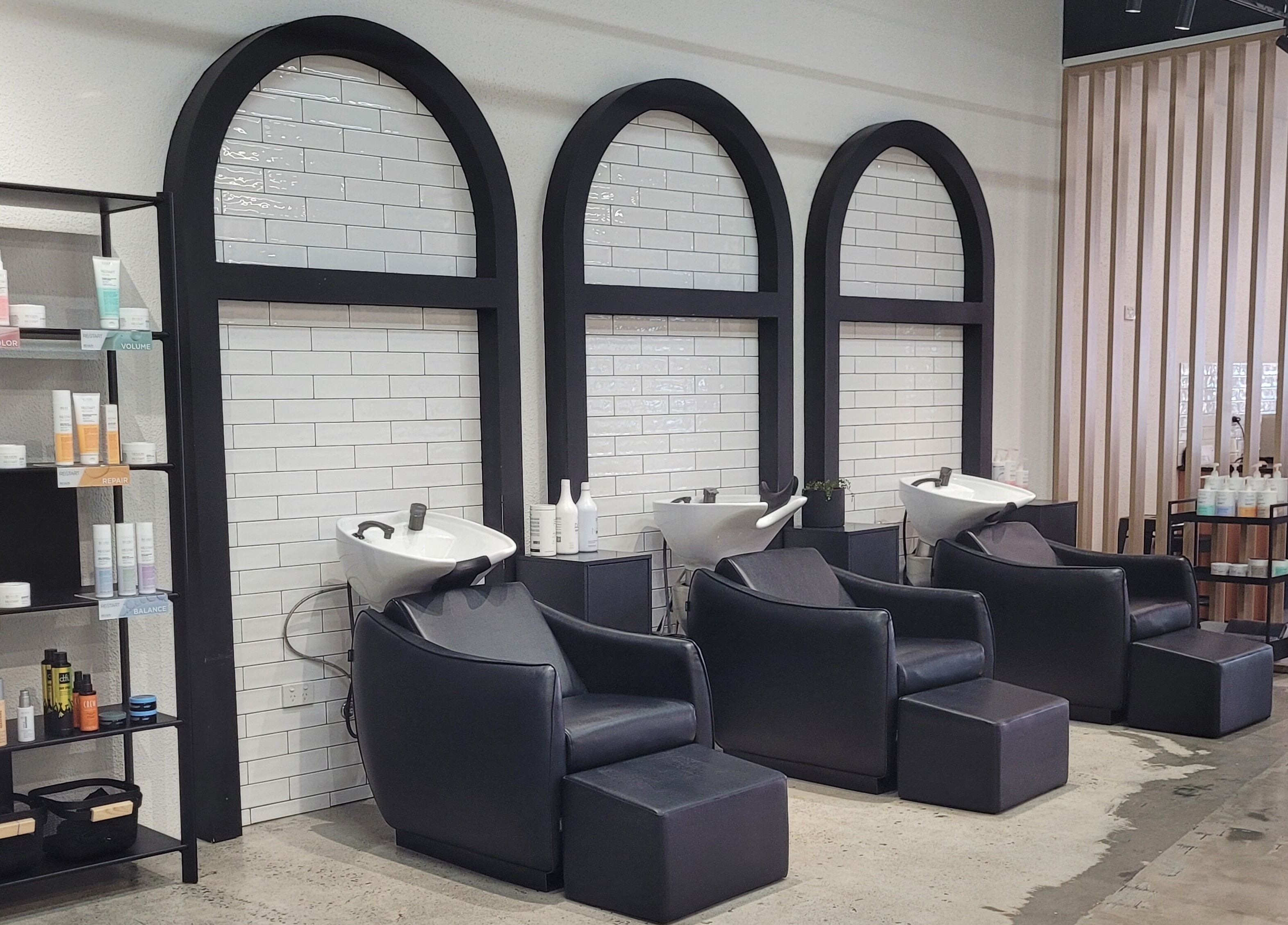 Luxurious wash stations at Kristy Campbell at Style Bar, Werribee, Victoria, AU with sleek black chairs and products.