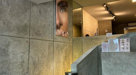 Lobby of Moonlash Studio Tukad Barito in Bali, Bali, ID, showcasing chic gray walls and beauty posters.