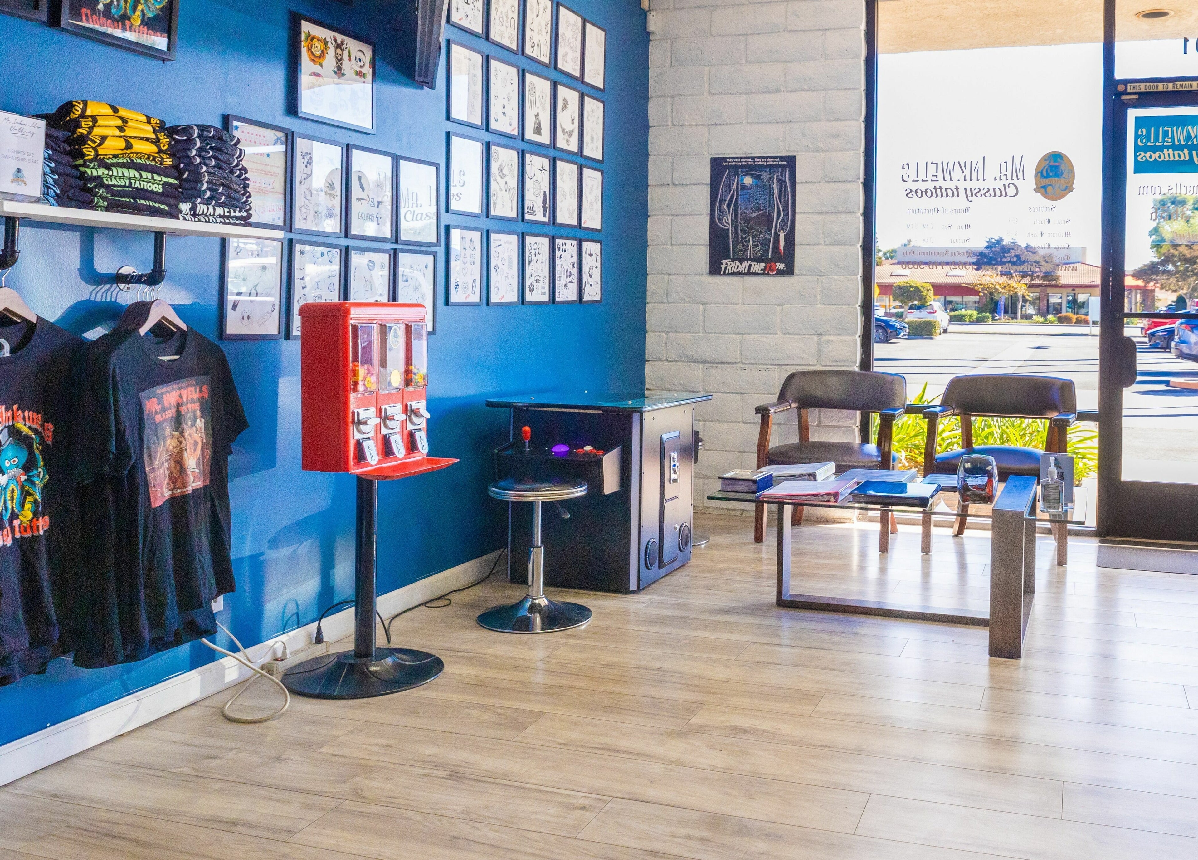 Interior of Mr. Inkwells in Los Alamitos, California, showcasing tattoo-themed t-shirts and waiting area.
