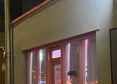Exterior of Rythm Barbering in Bristol, England, GB, warmly lit at night.