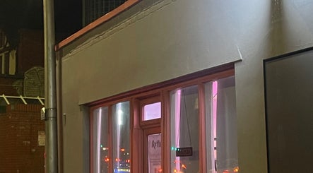 Exterior of Rythm Barbering in Bristol, England, GB, warmly lit at night.
