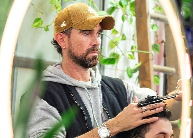 Stylist at Rythm Studio in Bristol, England, GB, expertly cuts a client's hair amidst a lush, plant-filled space.