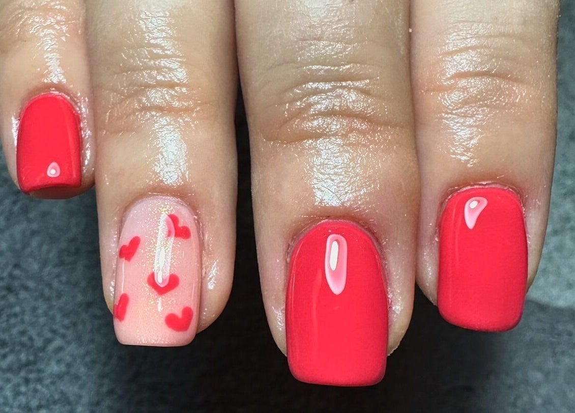 Red polished nails with heart designs at Sage beauty & aesthetics, Wigan, England, GB.