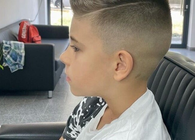 Момче със стилна прическа в Barber Studio Uppercut, Пловдив, Пловдив, BG, седнало на черен диван.