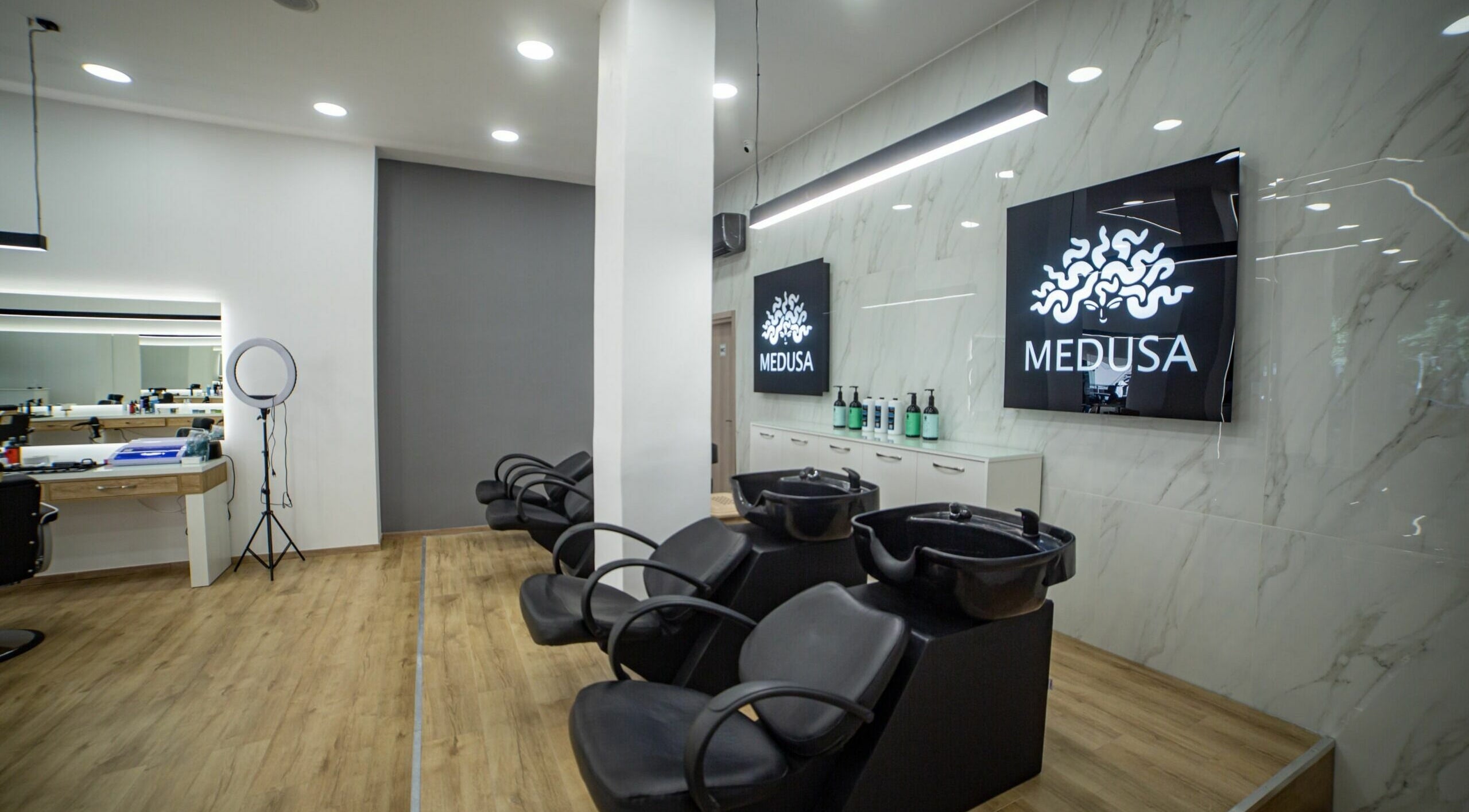 Εσωτερικό κομμωτηρίου Medusa Kordelio στο Ελευθέριο Κορδελιό, GR με μοντέρνα διακόσμηση και κομμωτήρια καθίσματα.