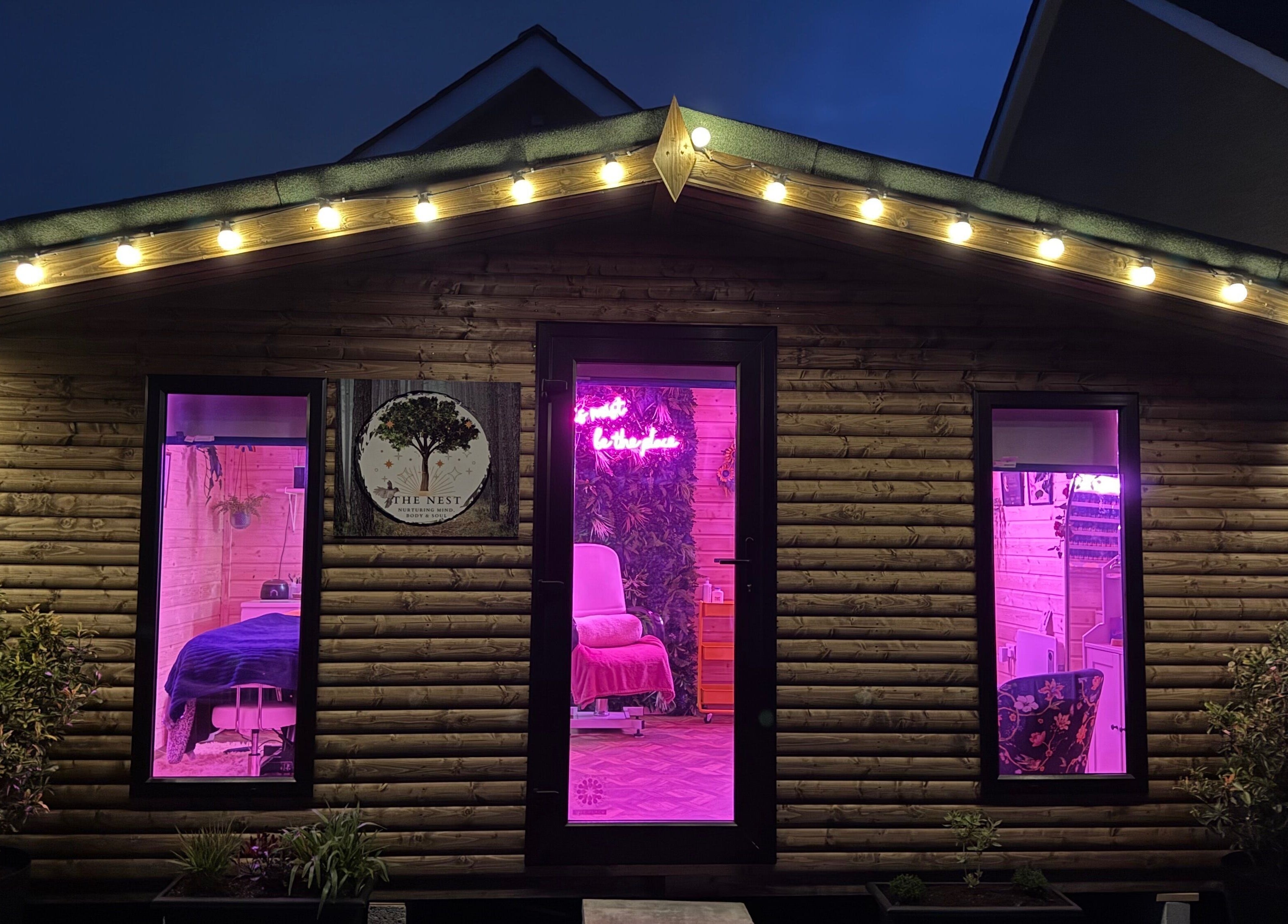 The Nest in Larne, Northern Ireland, GB featuring a charming wooden exterior with glowing pink lights.