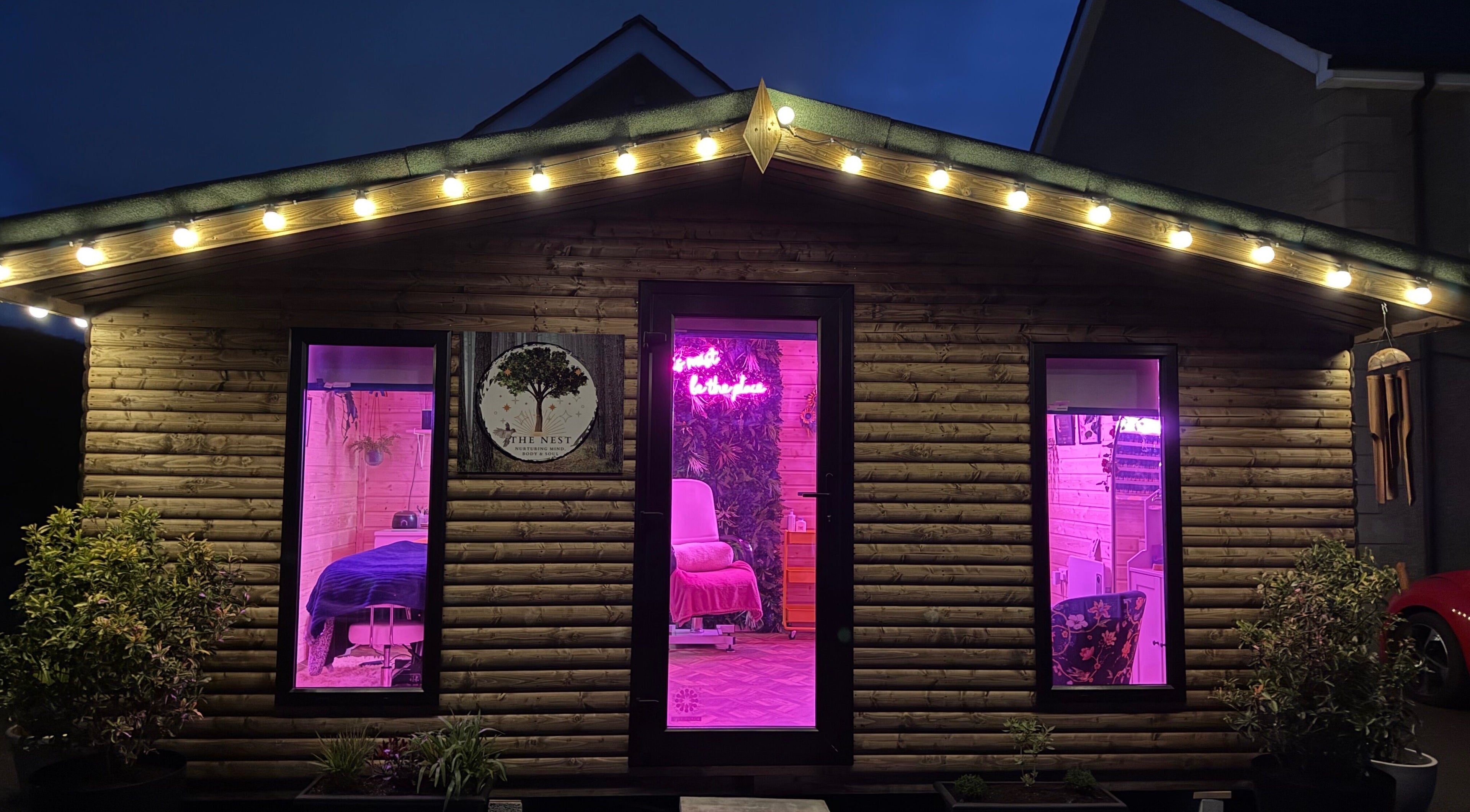The Nest in Larne, Northern Ireland, GB featuring a charming wooden exterior with glowing pink lights.