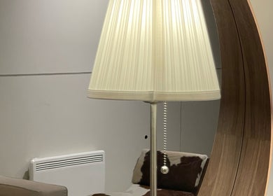 Warmly lit lamp beside plush sofa at Soso Beauty, Liverpool, England, GB, reflecting in a stylish mirror.