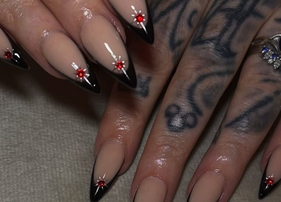 Elegant stiletto nails with black tips and red gems at Normandaé Studio, Saltash, England, GB.