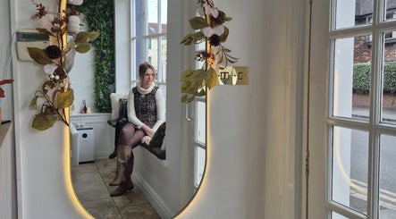 Chic interior with a mirror and a seated guest at Hair By Helena, Nantwich, England, GB.