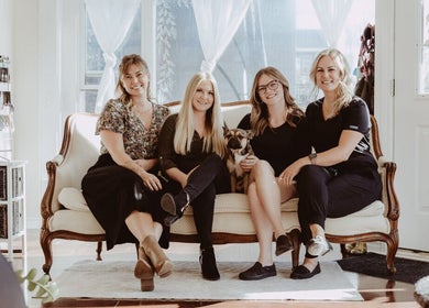 The Beauty Loft team at Marmora, Ontario CA, smiling on a vintage sofa with a dog.