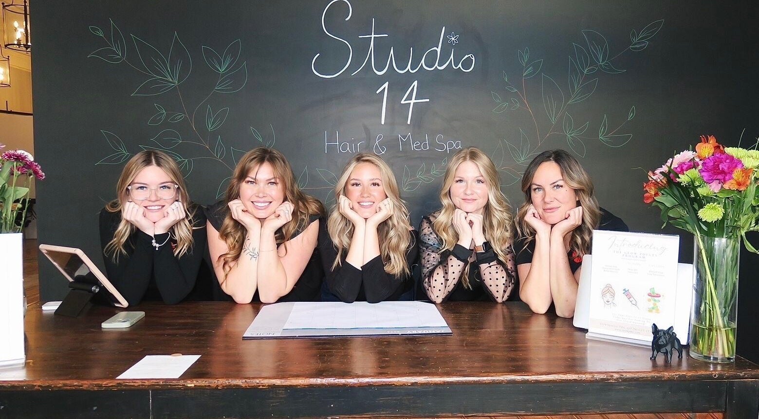 Team at Studio 14 Hair & Med Spa, Marmora, Ontario, CA, smiling behind a welcoming counter.