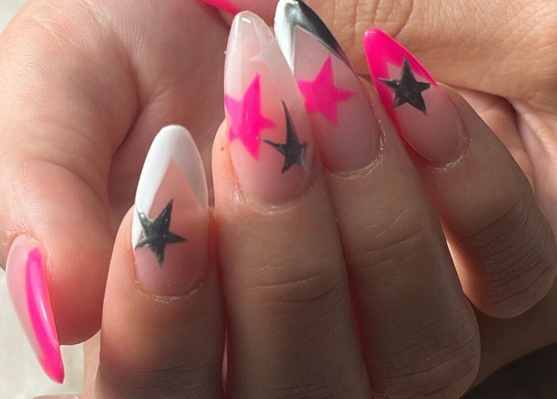 Vibrant star-themed nail art at Nails and Tails, Clevedon, England, GB, showcasing pink and black designs.