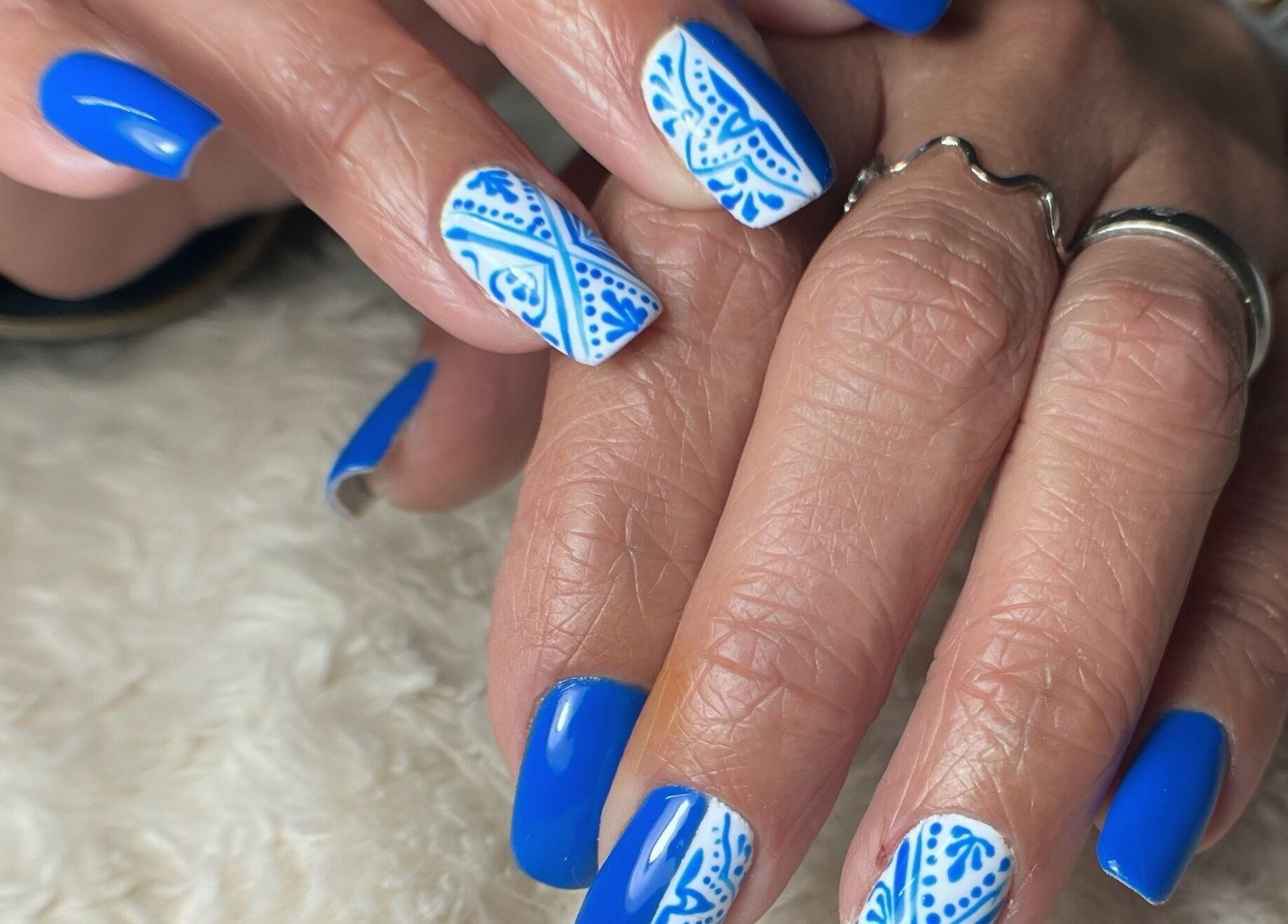 Elegant blue nails with intricate white design at Nails and Tails, Clevedon, England, GB.