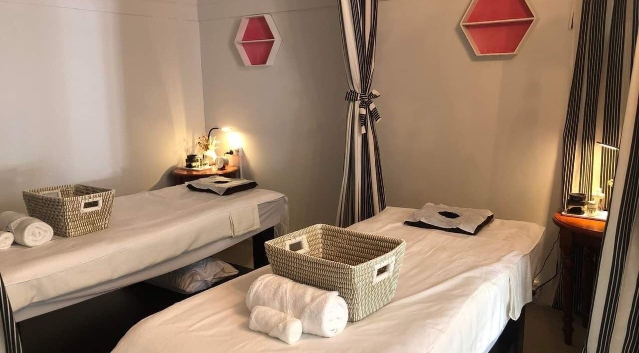 Cozy massage room at Like's Massage, The Junction, New South Wales, AU, featuring two tables and soft lighting.