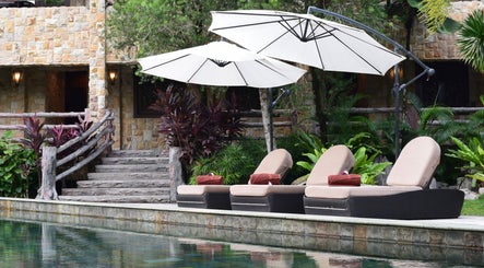 Relaxing poolside chairs at Sembunyi Spa in Cyberjaya, Selangor, MY, surrounded by lush greenery.