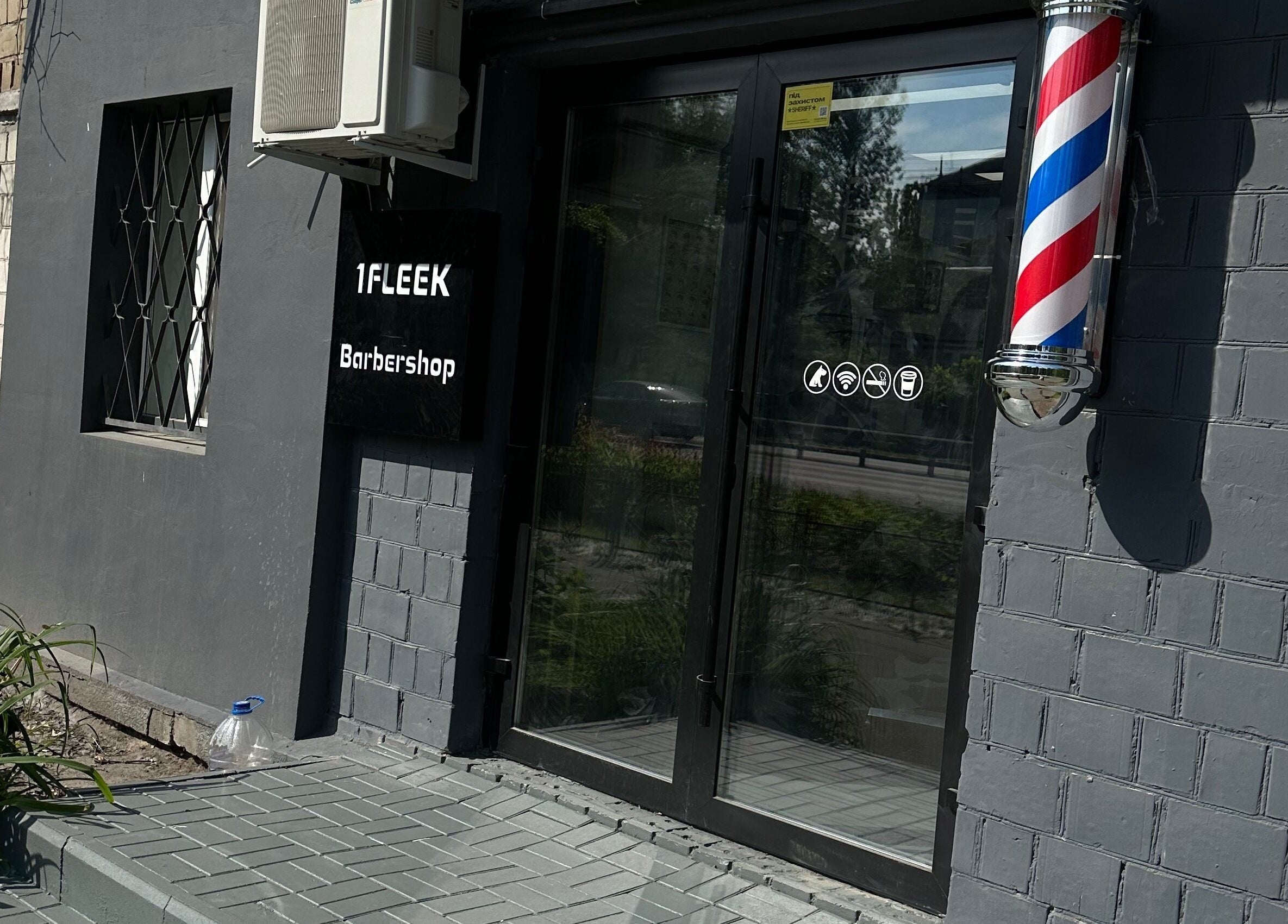 Вхід до 1 Fleek Barbershop у Києві, стильний фасад з барберським знаком.