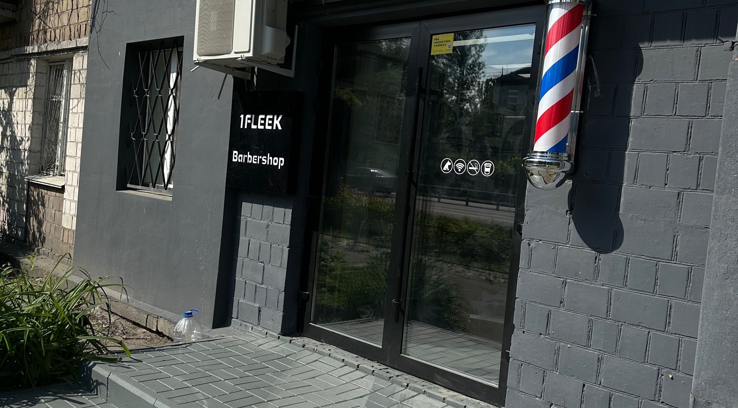 Вхід до 1 Fleek Barbershop у Києві, стильний фасад з барберським знаком.