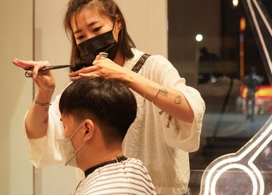 Stylist at WECUT惟理髮 giving a haircut in New Taipei City, TW. Modern and skilled hair styling service.