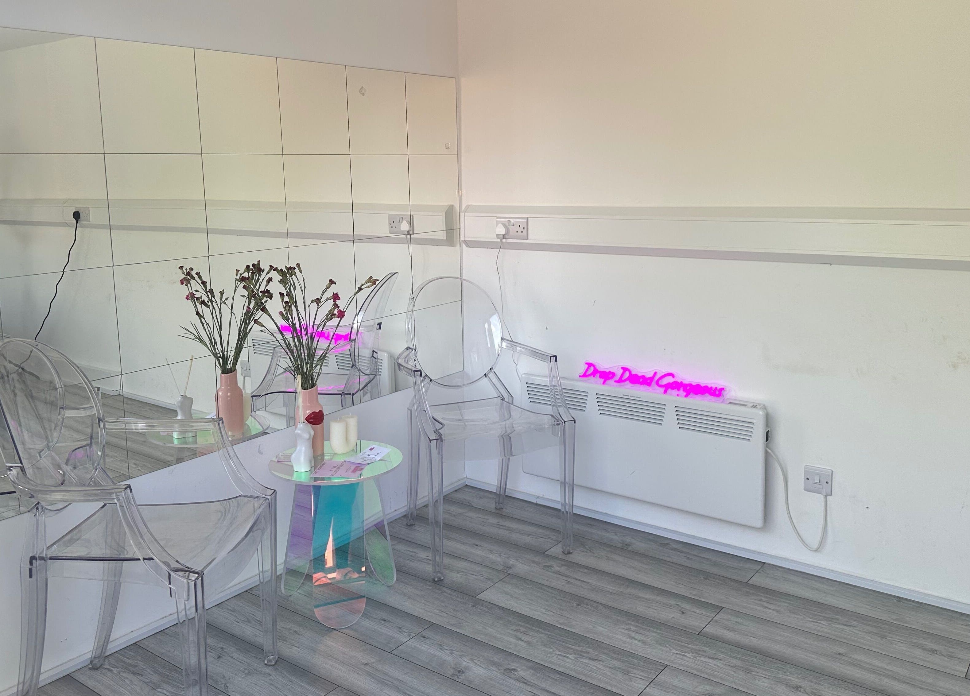 Elegant waiting area at Beauty Plug by Kirsty, Reading, England with clear chairs and mirrored walls.