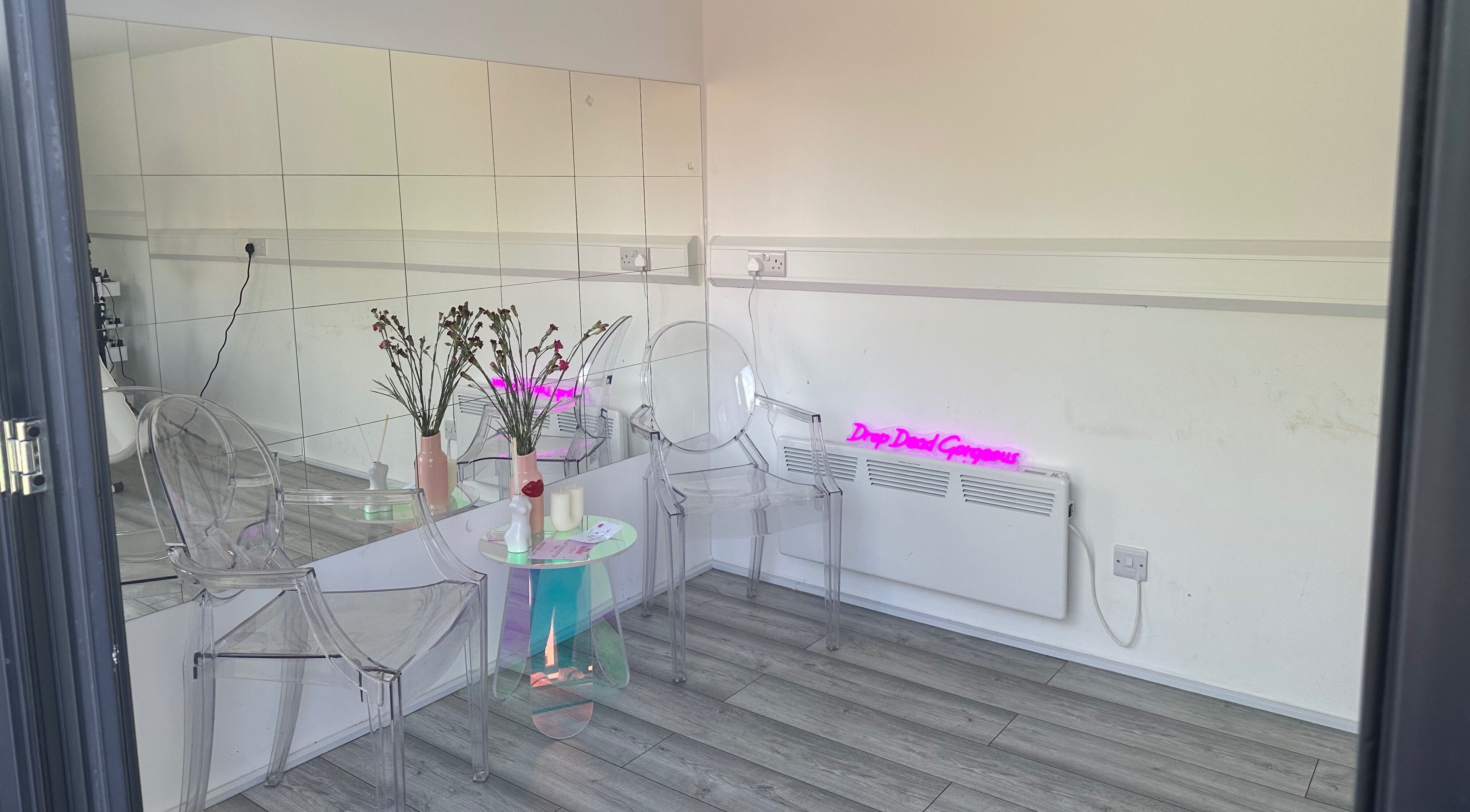 Elegant waiting area at Beauty Plug by Kirsty, Reading, England with clear chairs and mirrored walls.