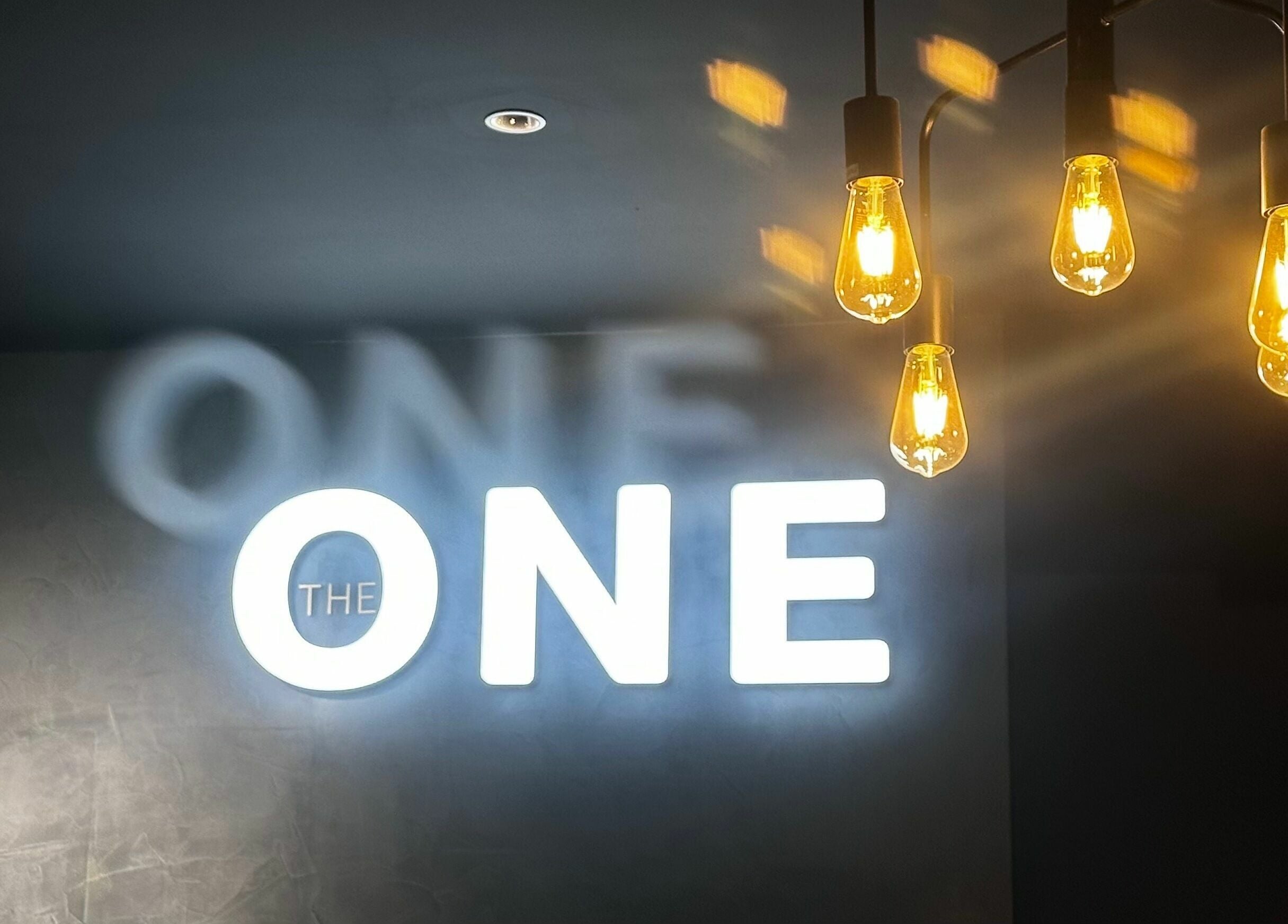 Illuminated sign and lights at The One Fashion Hair, Melbourne, Victoria, AU convey warmth and style.