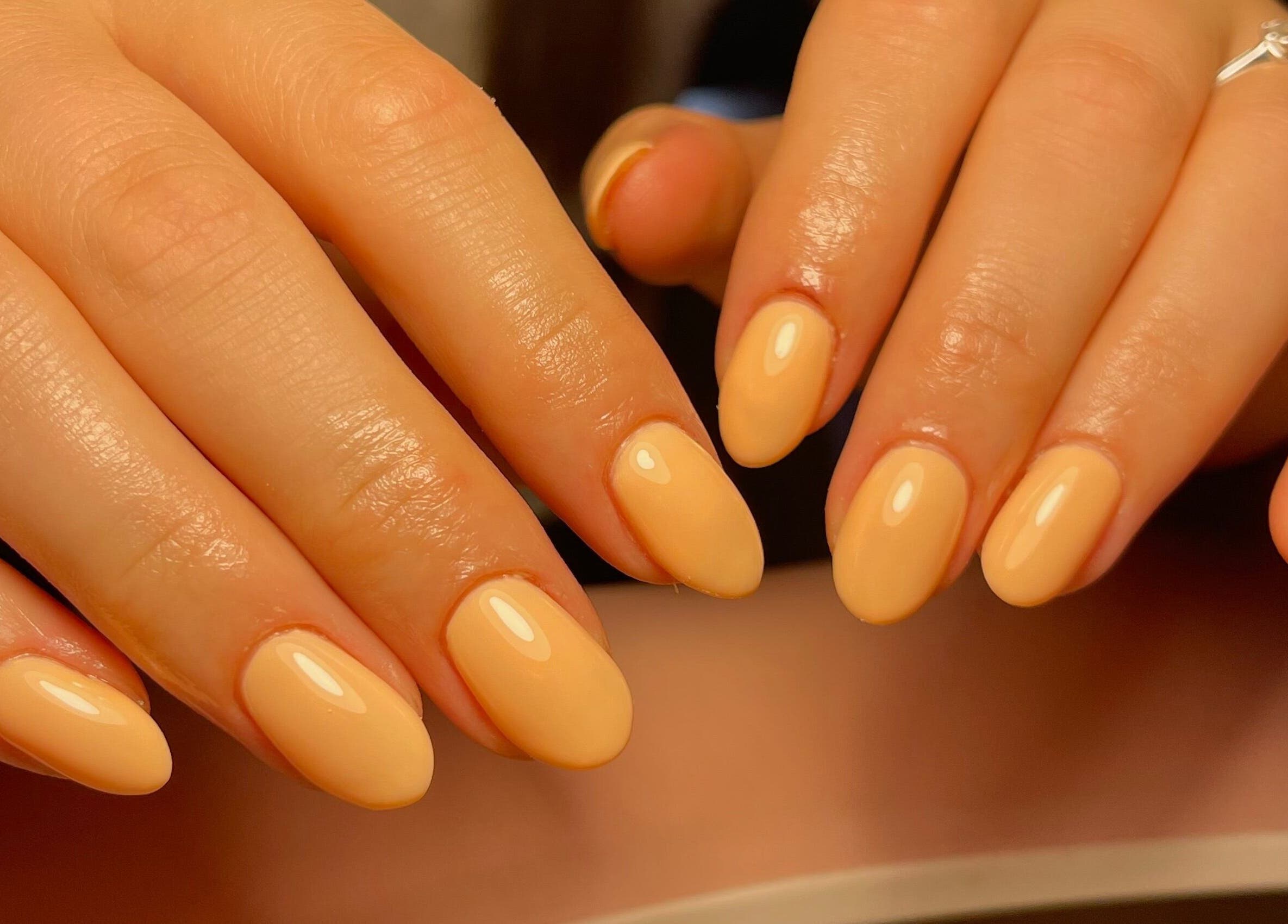 Elegant manicured hands with peach nails at Neuro Nails, Blenheim, Marlborough, NZ.