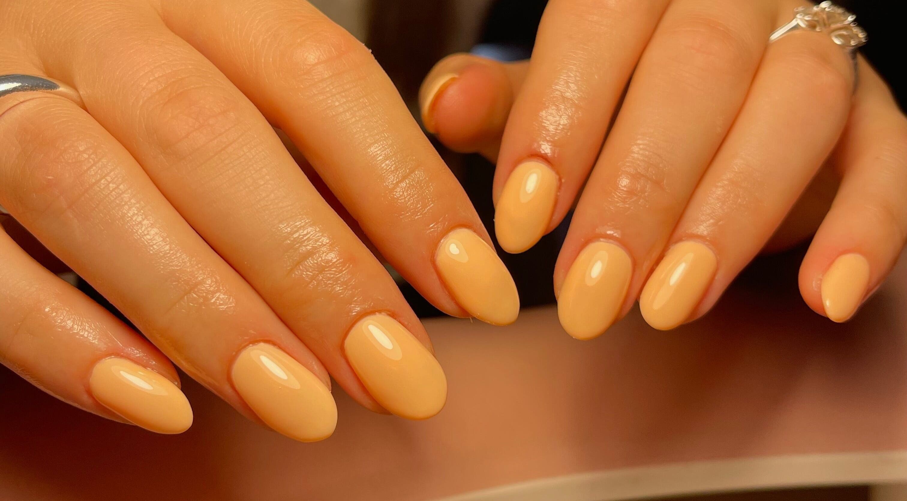 Elegant manicured hands with peach nails at Neuro Nails, Blenheim, Marlborough, NZ.